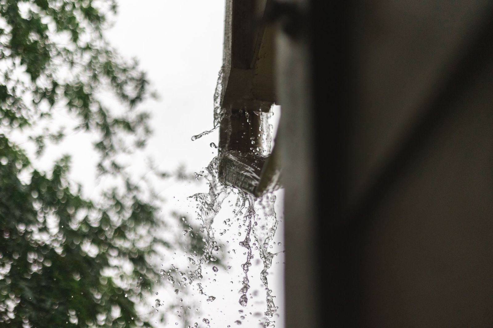Regenwasser schießt bei starkem Regen aus einer überlaufenden Dachrinne